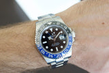 Stainless steel Swiss luxury watch with black and blue bezel on wrist, close-up shot