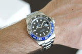 Luxury stainless steel GMT watch with black and blue bezel on wrist, close-up view