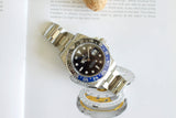 Stainless steel GMT watch with black and blue bezel on open book background
