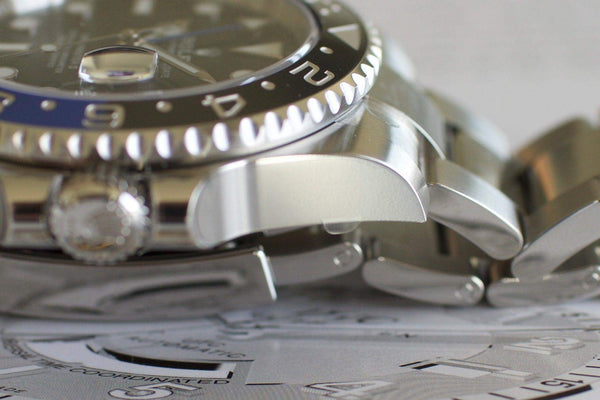 Close-up of stainless steel luxury watch case, bezel, and bracelet on printed background