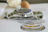 Close-up of luxury Swiss-made stainless steel watch with blue and black bezel, showing dial components