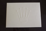 White luxury watch box with an embossed crown logo on a dark background