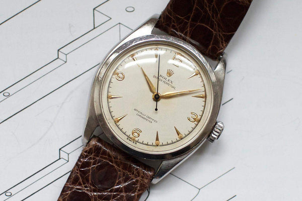 Vintage luxury Swiss watch with cream dial, gold markers, brown leather strap, and stainless case