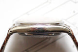 Side view of vintage steel watch case with domed crystal and leather strap