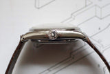 Side view of vintage luxury watch with domed crystal and brown leather strap