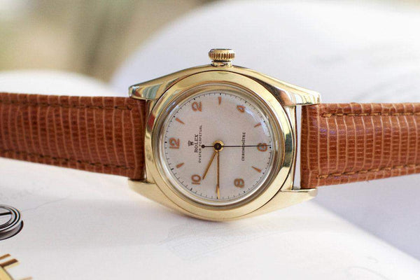 Vintage gold wristwatch with brown textured leather strap and classic round dial