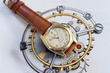 Vintage gold Swiss watch with brown leather strap on mechanical illustration