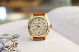 Vintage gold Rolex Oyster Perpetual Bubbleback watch with leather strap on open book