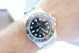 Close-up of a Rolex Submariner luxury watch with a black dial on a person's wrist