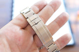 Close-up of a stainless steel Rolex watch bracelet held in a hand.