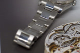 Stainless steel luxury watch bracelet beside intricate mechanical watch movement
