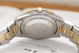 Close-up of vintage two-tone luxury watch case back and bracelet on an open book