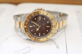 Vintage two-tone GMT watch with brown dial and gold bezel on a book background