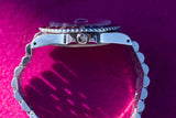 Side view of a luxury stainless steel watch with a jubilee bracelet against a purple background
