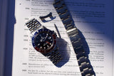 Rolex Explorer II luxury watch with white dial and steel bracelet resting on text.