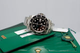 Stainless steel GMT watch with black bezel on green display box and certification cards