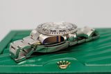 Close-up side view of a stainless steel Swiss luxury watch with black bezel on a green box