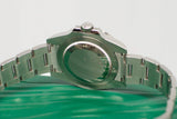 Stainless steel luxury watch caseback and bracelet close-up on green surface