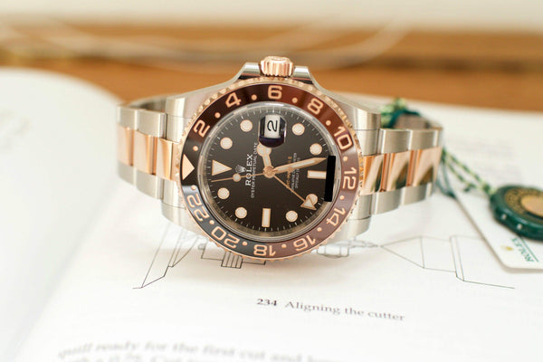 Two-tone Rolex GMT-Master II Root Beer watch with black and brown bezel on open book