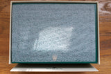 Closed green luxury watch box with textured protective cover, gold crown logo visible
