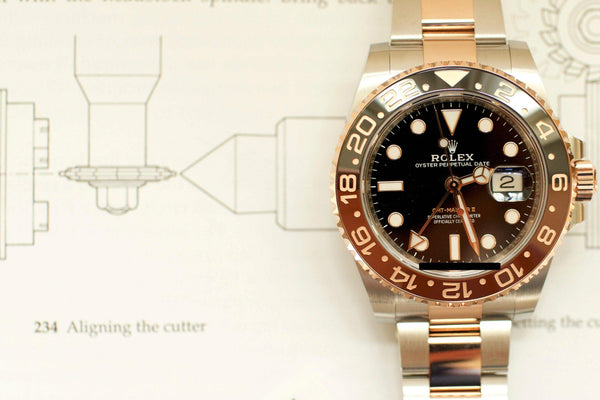 Two-tone Rolex GMT-Master II Root Beer watch with black and brown bezel on technical drawing background