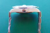 Side view of a luxury stainless steel watch with a link bracelet on a green background