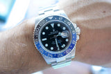 Close-up of a Rolex GMT-Master II luxury watch with a blue and black bezel on a wrist.