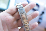 Close-up of a stainless steel luxury watch bracelet clasp held in a hand