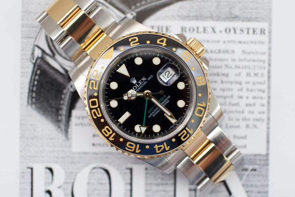 Two-tone Rolex GMT-Master II watch with black dial and ceramic bezel on a magazine background