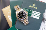Two-tone luxury GMT watch with black dial and ceramic bezel on warranty papers