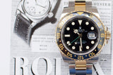 Two-tone luxury GMT watch with black bezel and gold accents, placed on watch magazine.