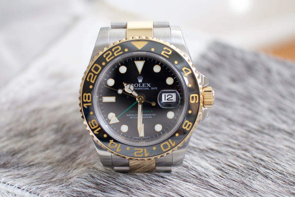 Two-tone GMT luxury Swiss watch with black ceramic bezel and date display on fur surface
