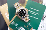 Two-tone stainless steel and gold GMT luxury watch with black ceramic bezel, displayed on warranty cards and booklets.