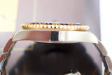 Close-up side view of luxury two-tone GMT wristwatch with gold bezel and metal bracelet