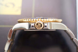 Close-up side view of a two-tone gold and stainless steel luxury watch crown and bezel
