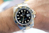 Two-tone stainless steel and gold GMT luxury watch with black dial on wrist