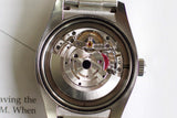 Close-up of luxury Swiss watch movement with visible gears and stainless steel case
