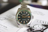 Stainless steel Rolex Milgauss luxury watch with black dial and orange accents on paper