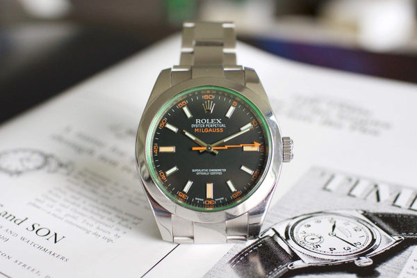 Stainless steel Rolex Milgauss luxury watch with black dial and orange accents on paper