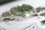 Close-up of luxury stainless steel wristwatch with green bezel and black dial