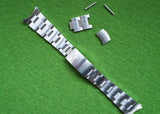 Silver luxury watch bracelet with detached links and pins on a green surface