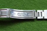 Close-up of a Rolex stainless steel watch bracelet clasp with engravings.