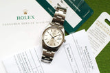 Pre-owned Rolex Oysterdate watch with silver dial and steel bracelet on service paperwork.