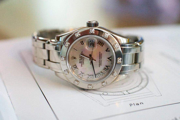 Silver women’s luxury watch with diamond bezel, Roman numeral dial, and date display