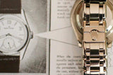 Close-up of luxury watch metal bracelet clasp with crown emblem, over vintage watch magazine