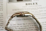 Side view of a silver women's luxury watch with diamond markers on a printed document