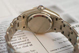 Close-up of a luxury women's stainless steel watch case and bracelet on printed paper