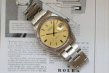 Stainless steel vintage watch with champagne dial and date window on an open magazine