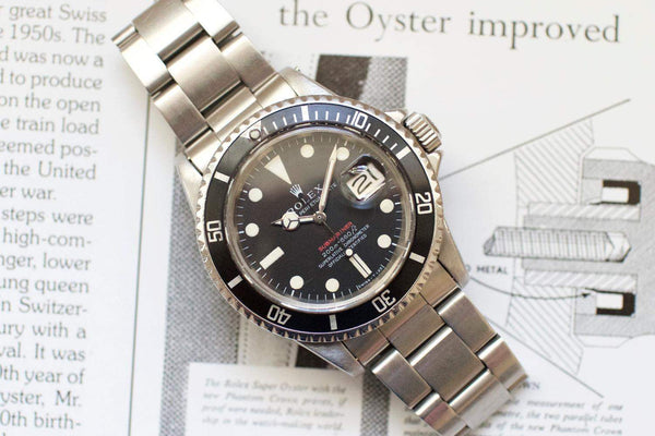 Vintage stainless steel dive watch with black bezel and date display on open book
