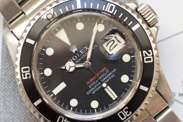 Close-up of vintage stainless steel Swiss dive watch with black dial and date window